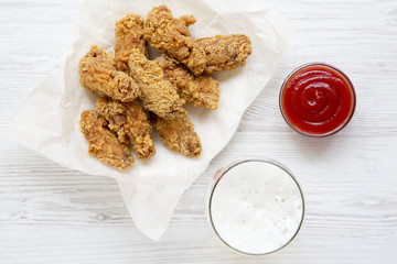 Fried chicken wings with red pepper sauce, cold beer, top view. Flat lay, overhead.