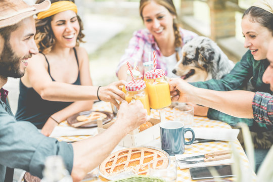 Happy millennial friends cheering at breakfast brunch meal in nature outdoor