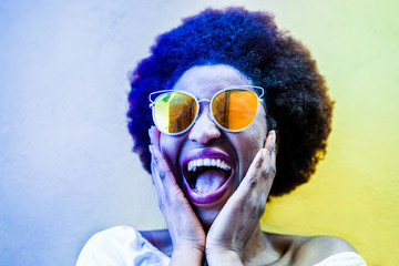Millennial african woman smiling and wearing yellow sunglasses - obrazy, fototapety, plakaty