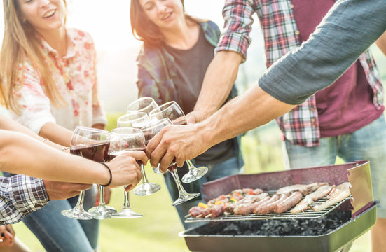 Happy millennial friends cheering with  wine at barbecue outdoor