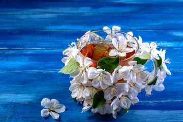 Cup decorated with white flowers of apple trees on a blue wooden background.