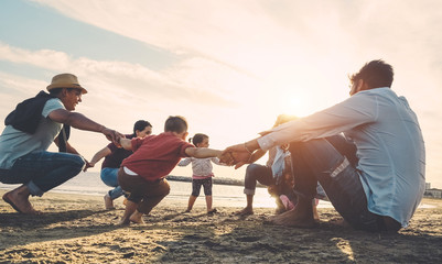 Family friends having fun on the beach at sunset