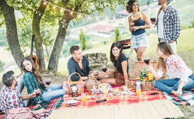 Happy millennials friends haing picnic bbq dinner outdoor