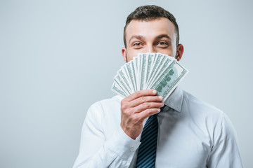 happy financier looking out from dollar banknotes isolated on grey