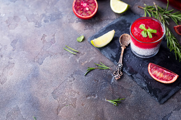 Chia pudding with fresh berries puree and honey with slice citrus on slate dark background. Superfoods concept. Copy space with flat lay