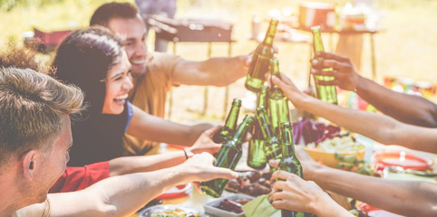 Obraz premium Happy millennial friends cheering with beers at barbecue party in nature