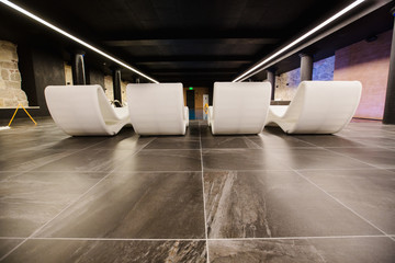 Soft white modern beach beds stand around the swimming pool inside the hotel