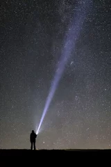 Rolgordijnen Silhouette of a tourist with a flashlight, observing beautiful, wide blue night sky with stars and galaxies © Mazur Travel