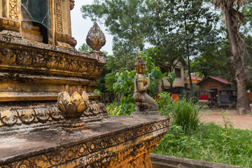 detail of decorative ornaments of golden stupa with a tuk tuk in the background in buddhist temple in cambodia