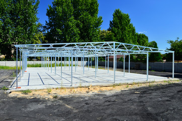 Metalowa kratownica budynku na betonowym fundamencie w trakcie budowy.