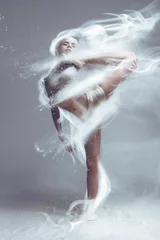  Dansen in meel. Roodharige spier performer vrouw danser in stof/mist. Meisje dragen witte top en shorts maken danselement in bloem wolk op geïsoleerde achtergrond. Surrealistisch begrip. © Monstar Studio