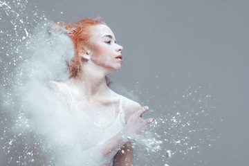 Dancing in flour concept. Naked redhead woman dancer in dust / fog. Portrait of a girl dancer with...