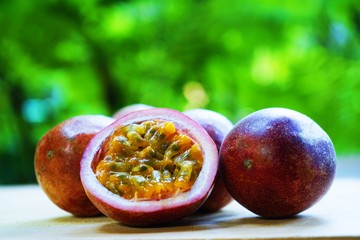Group of passion fruit with half cut on wooden table with blur green garden background, copy space,...