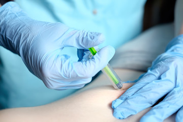 hands of nurse in blue surgical gloves making injection of anticoagulant subcutaneously
