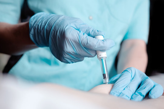 hands of nurse in blue surgical gloves making injection of anticoagulant subcutaneously