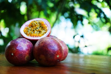 Fototapeta na wymiar Group of passion fruit with half cut on wooden table with blur green garden background, copy space, healthy food concept