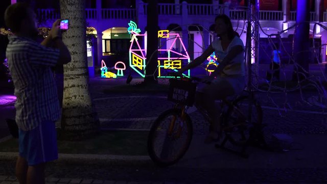 LED bicycle ride. A man is taking pictures of a woman on a smartphone