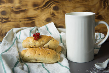 White cup with tasty croissants on white  tablecloth with small red berries