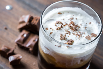 white russian cocktail with kahlua vodka and cream and chocolate pieces on wooden background