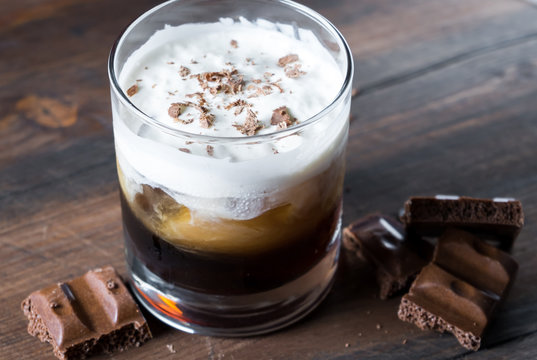 White Russian Cocktail With Kahlua Vodka And Cream And Chocolate Pieces On Wooden Background