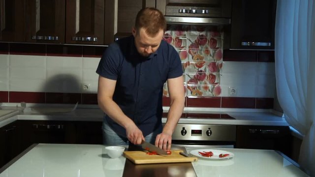 Slicing Red chili pepper. A man cuts pepper on a wooden Board