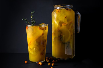 cocktail with orange juice, lemon, ginger, sea ​​buckthorn, thyme on black background