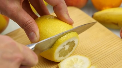 Woman slices the citrus fruit on a wooden cutting board with variety of fruits around. Weight loss and dieting concept. slow motion