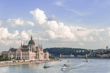 Fototapeta premium Budapest skyline with the Hungarian Parliament building, ships sailing on the Danube river and Gellert Hill under the blue cloudy sky
