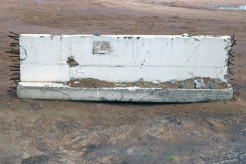 concrete slab with protruding rusty fittings on sand