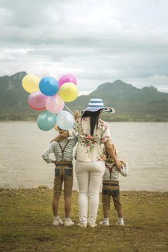 Happy family holding colorful balloons outdoor.
