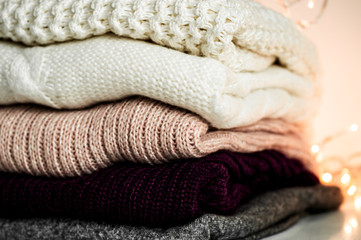 Fototapeta na wymiar Warm sweaters. Pile of knitted clothes on warm background, sweaters, knitwear, space for text, Autumn winter concept. Copy Space