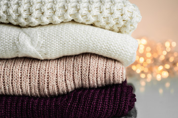 Warm sweaters. Pile of knitted clothes on warm background, sweaters, knitwear, space for text, Autumn winter concept. Copy Space