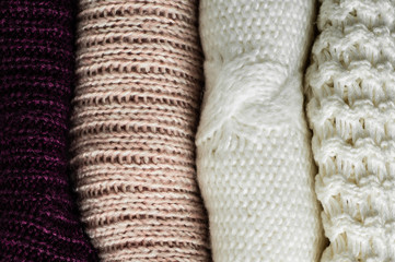 Warm sweaters. Pile of knitted clothes on warm background, sweaters, knitwear, space for text, Autumn winter concept. Copy Space