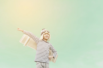 Happy child playing with toy wings against summer sky background.