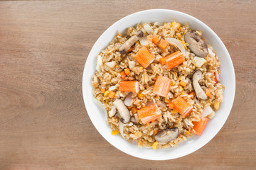 top view of fried rice with crab stick and vegetable in a ceramic dish on wooden table. asian homemade style food concept.