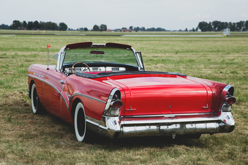 Classic red car parking on grass fields
