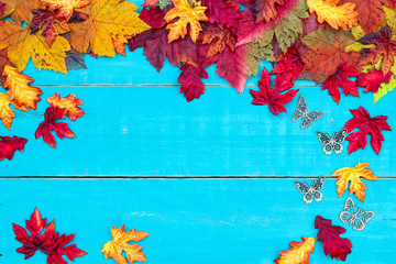 Blank antique rustic teal blue background with colorful autumn leaves and butterflies border; wooden fall sign with copy space