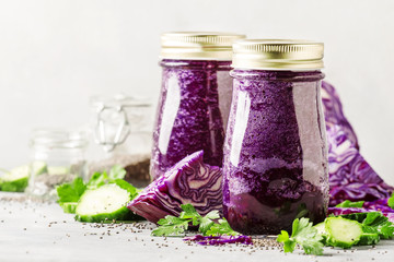 Healthy vegan detox purple smoothies or juice from red cabbage, cucumbers with chia seeds in glass bottles on  gray background, selective focus