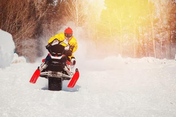 Tuinposter Snowmobile races jump in snow dust. Concept winter extreme sports © Parilov