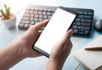 Hands holding blank screen smartphone at office desk