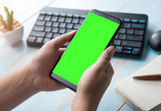 Hands Holding Blank Screen Smartphone At Office Desk