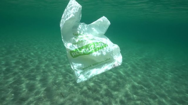 Plastic waste underwater, a reusable plastic bag in the Mediterranean sea between water surface and a sandy seabed, Almeria, Andalusia, Spain

