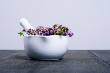 thyme flowers in a mortar on dark wood table