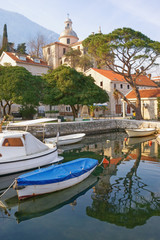 Fototapeta na wymiar Ancient Mediterranean town of Prcanj on winter day. Montenegro, Bay of Kotor, view of small harbor for fishing boats and Birth of Our Lady Church