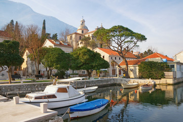 Fototapeta premium Ancient Mediterranean town of Prcanj on sunny winter day. Montenegro, Bay of Kotor, view of small harbor for fishing boats and Birth of Our Lady Church