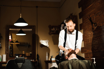 Master cuts hair and beard of men in the barbershop