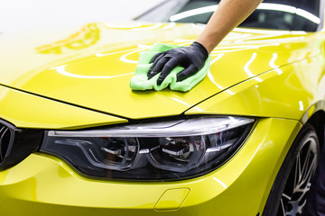 A man cleaning car with microfiber cloth, car detailing (or valeting) concept. Selective focus.