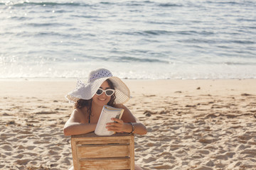 Young woman relaxing on the beach, reading a book. Leisure activity. Vacation concept