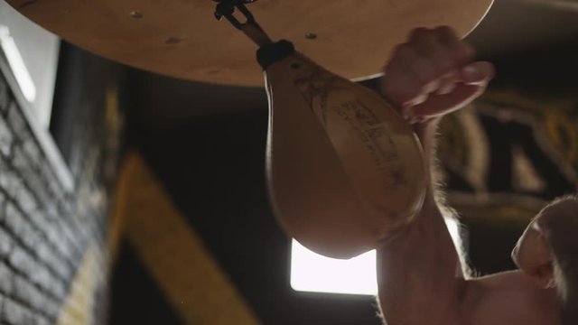 Fists of boxer hit punch bag. Preparing for boxing competition. Close up of male hands punching speed bag. Boxer training in boxing gym. Warm-up of boxer before competition. Man punching bag