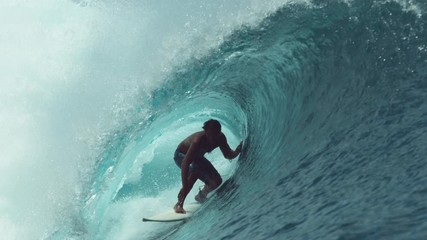 SLOW MOTION, CLOSE UP: Extreme sportsman having fun riding a beautiful barrel ocean wave. Breathtaking shot of active man on holiday surfing a perfect crystal clear hollow wave in Teahupoo, Tahiti. - Powered by Adobe